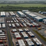 Aerial view of a busy UK industrial estate with factories, warehouses, and transport vehicles operating under cloudy skies