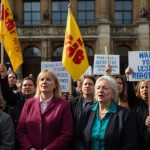 A group of disability rights activists holding signs and banners outside a government building, protesting against PIP benefit payment reforms.