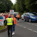 A group of residents holding signs at a roadside rally in Wrexham, advocating for and against the reversion of 20mph speed limits to 30mph.