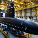 A Royal Navy submarine docked at a Babcock International facility, showcasing advanced naval maintenance operations.