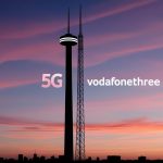 A VodafoneThree network tower stands tall against a vibrant sunset sky, symbolizing connectivity and innovation in the UK telecom industry.