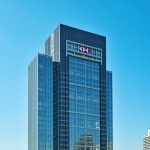 Modern glass building of HSBC's headquarters in Hong Kong under a clear blue sky, reflecting the bank's global presence.