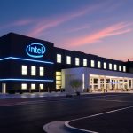 A modern Intel semiconductor factory illuminated at dusk, with sleek buildings and glowing lights, symbolizing advanced chip manufacturing.