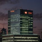 The iconic HSBC headquarters in Canary Wharf, London, illuminated against a twilight skyline, symbolizing the bank's bold acquisition of a 15% stake in Singapore's DBS Group.