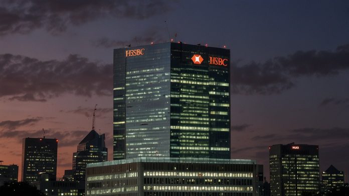 The iconic HSBC headquarters in Canary Wharf, London, illuminated against a twilight skyline, symbolizing the bank's bold acquisition of a 15% stake in Singapore's DBS Group.