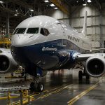 Boeing 737 MAX jet on assembly line at Renton facility under FAA investigation for production delays, with stock market chart showing 4% decline in September 2025.