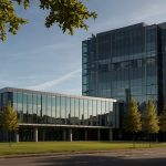 A modern glass building with the AstraZeneca logo prominently displayed, set against a backdrop of the London skyline, symbolizing the company's dual commitment to UK roots and global expansion.