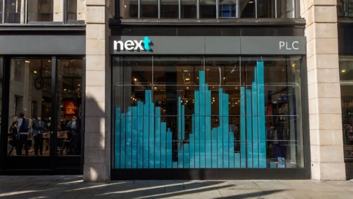 Next Shares Surge to Record High After £1.135 Billion Profit Upgrade Next plc logo on a London storefront with rising stock chart overlay showing 3% gain on FTSE 100, October 29 2025