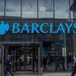 Barclays headquarters at One Churchill Place in Canary Wharf, London, with the Barclays logo prominently displayed against a clear blue December sky as the bank’s share price climbs 1.6% following positive Bank of England stress test results on 3 December 2025.
