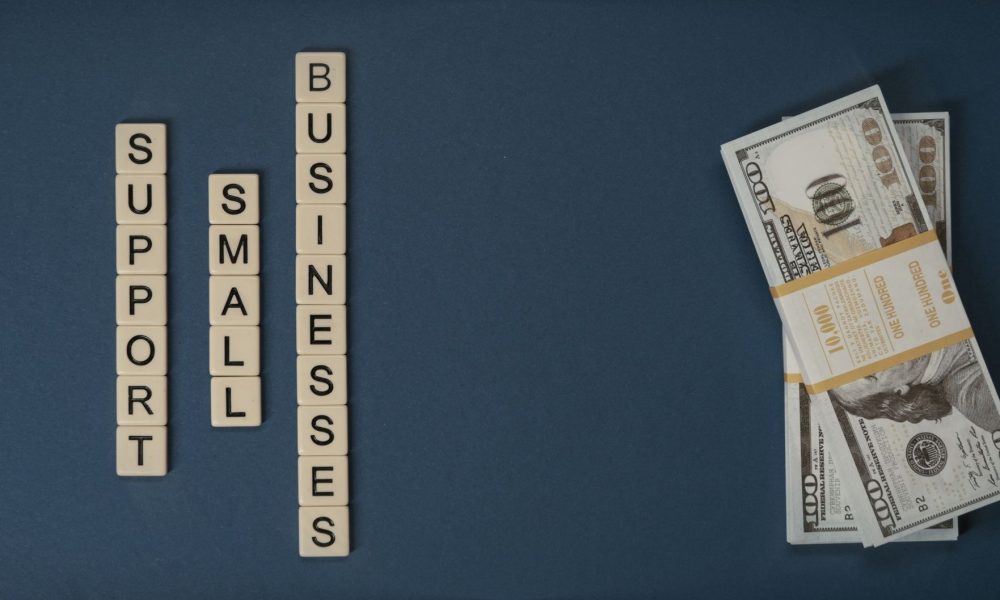 Dollar bills beside letter tiles spelling small businesses