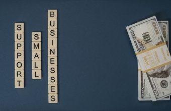 Dollar bills beside letter tiles spelling small businesses