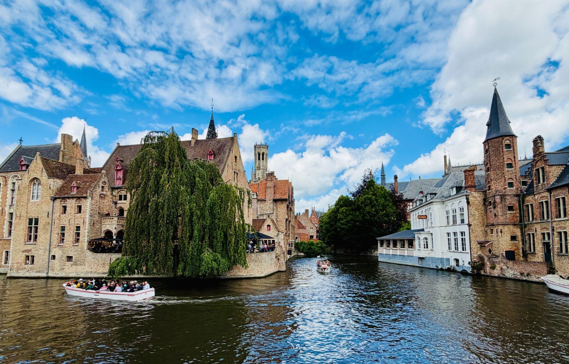 Tour boats on a canal in Bruges, Belgium, beside historic brick buildings