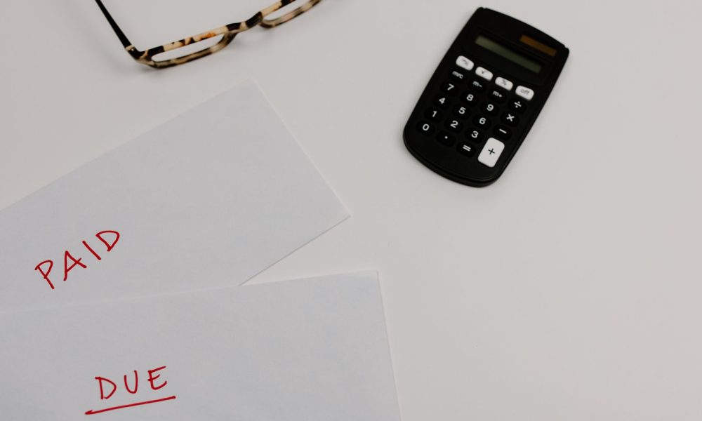 Paperwork marked paid and due beside a calculator, illustrating accounts receivable tracking