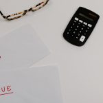 Paperwork marked paid and due beside a calculator, illustrating accounts receivable tracking