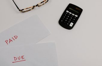 Paperwork marked paid and due beside a calculator, illustrating accounts receivable tracking
