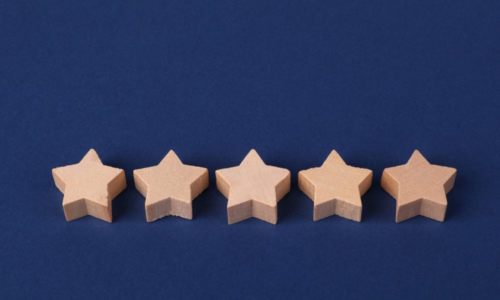 Five wooden stars on a blue background representing online reviews and reputation ratings