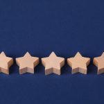 Five wooden stars on a blue background representing online reviews and reputation ratings