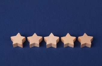 Five wooden stars on a blue background representing online reviews and reputation ratings