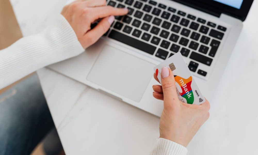 A person holding a credit card while shopping online on a laptop