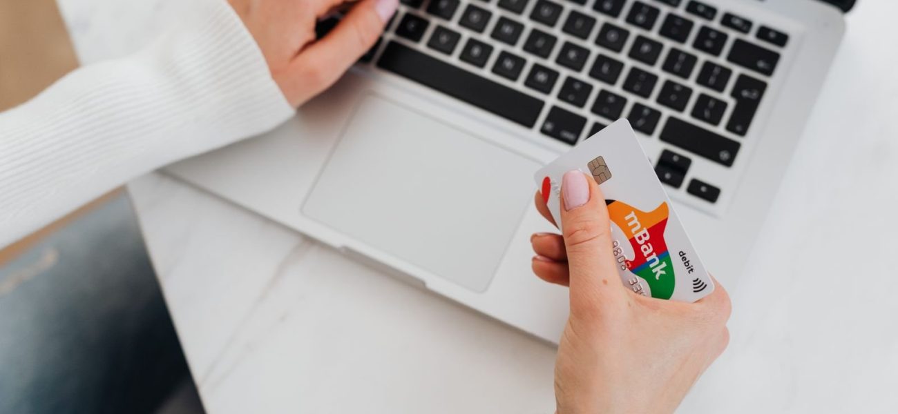 A person holding a credit card while shopping online on a laptop