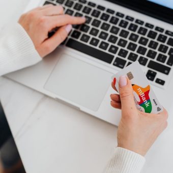 A person holding a credit card while shopping online on a laptop