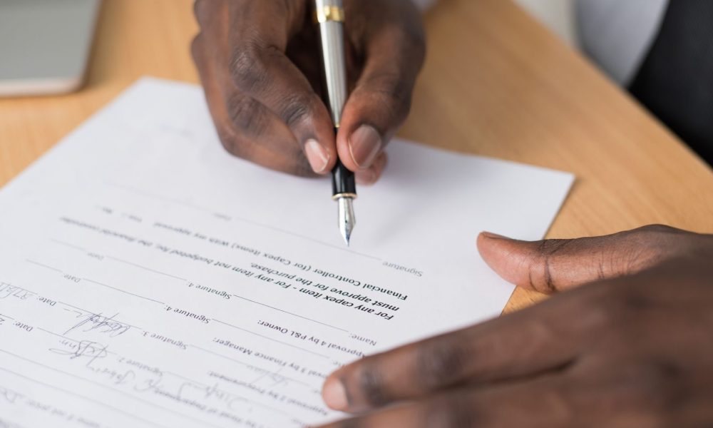 Close-up of a hand signing a formal business contract with a fountain pen