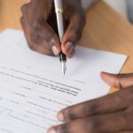 Close-up of a hand signing a formal business contract with a fountain pen