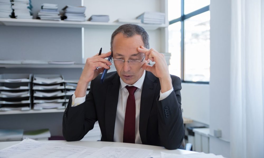Businessman in a suit on the phone reviewing documents, illustrating the hidden costs of business disruption