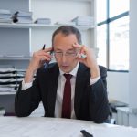 Businessman in a suit on the phone reviewing documents, illustrating the hidden costs of business disruption