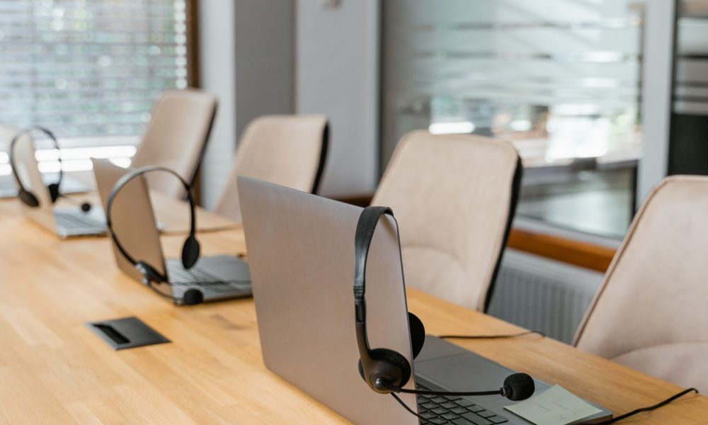 Laptops and headsets lined up on a contact centre desk, illustrating the CapEx and OpEx of a cloud contact centre migration