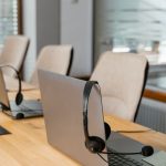 Laptops and headsets lined up on a contact centre desk, illustrating the CapEx and OpEx of a cloud contact centre migration