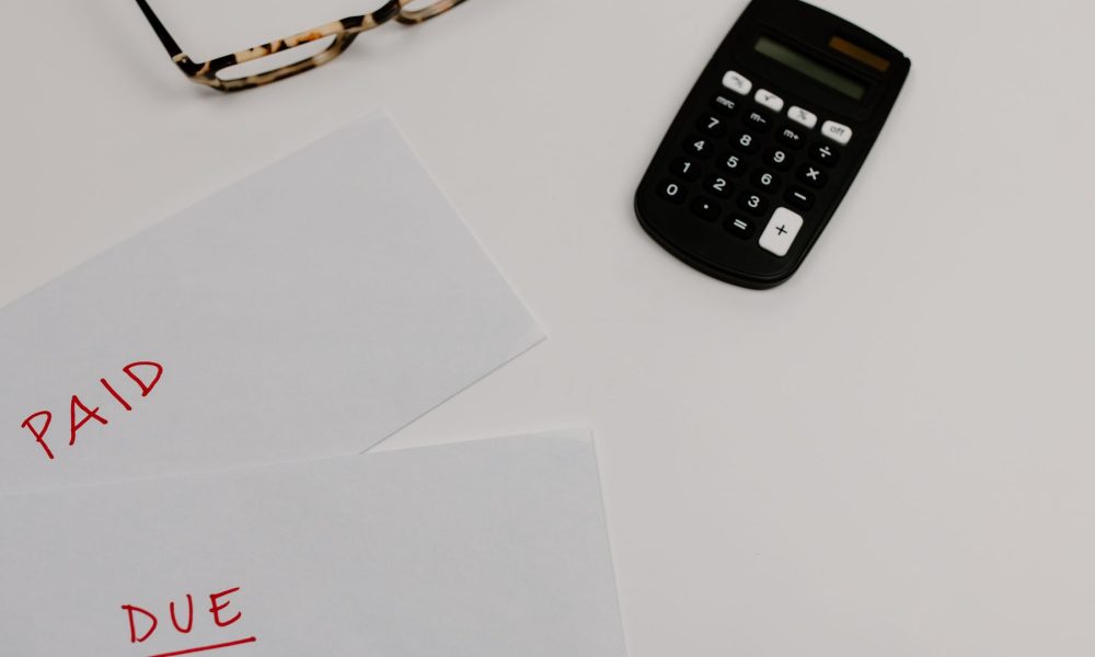 Paperwork marked paid and due beside a calculator, illustrating debt consolidation with bad credit
