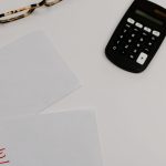 Paperwork marked paid and due beside a calculator, illustrating debt consolidation with bad credit