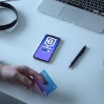 Person holding a crypto payment card beside a smartphone showing a blockchain app