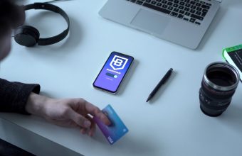 Person holding a crypto payment card beside a smartphone showing a blockchain app