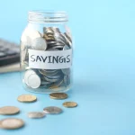 Savings jar of coins beside a calculator